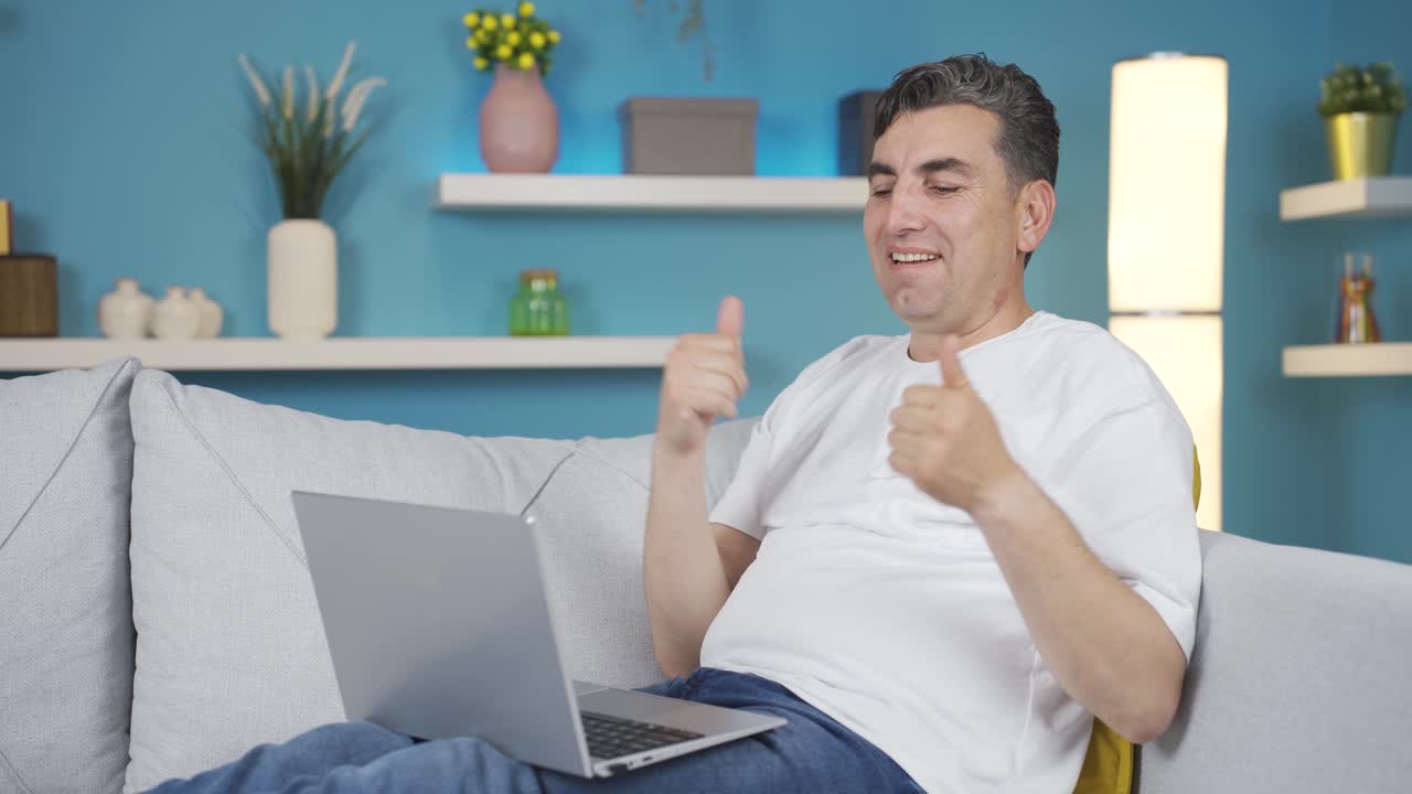 Man following work on laptop with relaxed and happy expression.