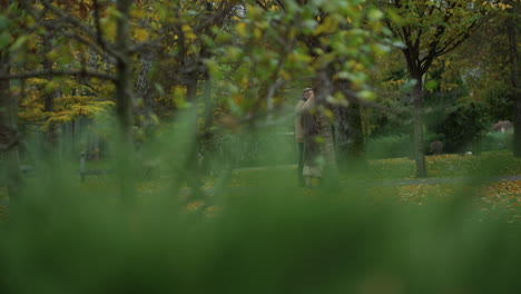 Long-shot-of-aged-pair-of-loving-man-and-woman-walking-at-nature-at-autumn-park