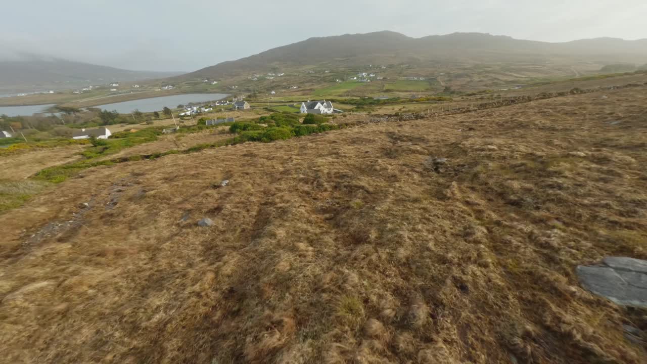 avión no tripulado volando rápidamente cuesta abajo hacia una casa blanca en la isla de achill durante la puesta de sol