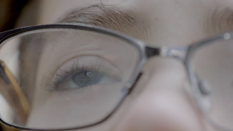 primer plano de los ojos azules de un joven con gafas mirando hacia arriba con esperanza