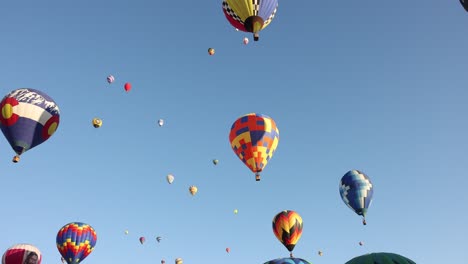 Free-flying-colorful-and-vibrant-hot-air-balloon-floating-with-other-balloons-ascending-on-a-clear-early-morning-mass-ascension-at-the-Albuquerque-Balloon-Fiesta-in-slow-motion