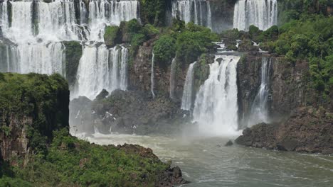 hermosa vista tranquila de cascadas en cámara lenta que se acumulan en una increíble piscina de inmersión en el verde bosque tropical, muchas cascadas dobles que se estrellan en el paisaje rocoso húmedo en las cataratas de iguazu, brasil