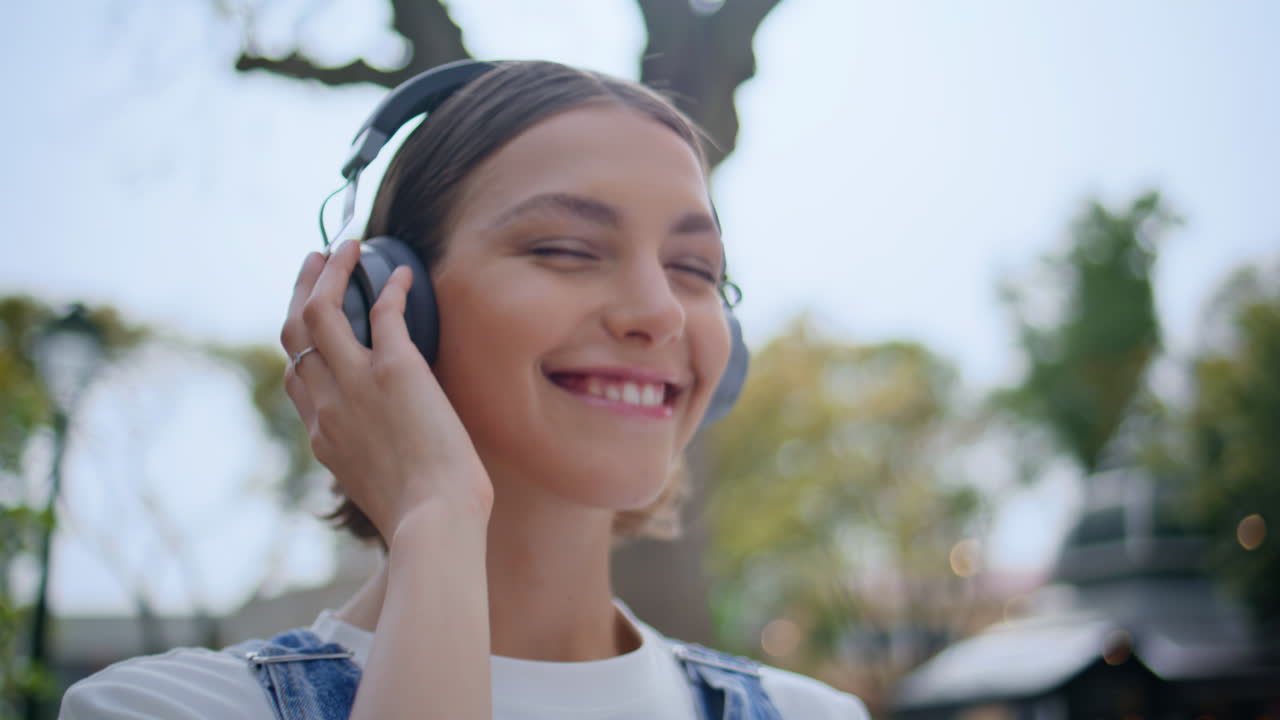 Teen listening sound earphones standing summer city street closeup. Smiling girl