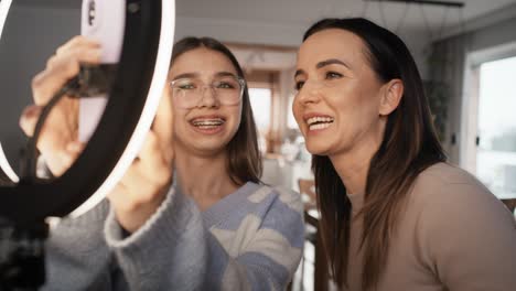 una adolescente y su madre grabando un baile para las redes sociales usando un teléfono móvil