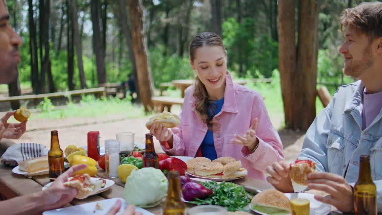 Friends eating sandwiches together at sunny picnic closeup. Happy men woman