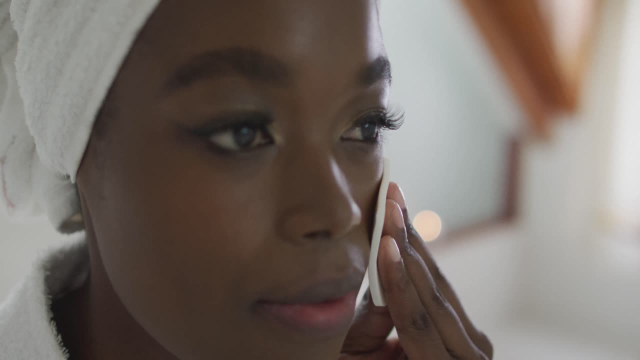 Portrait of african american attractive woman removing make up in bathroom