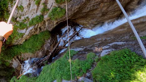 un hombre caminando sobre un puente de cable a través de una cascada