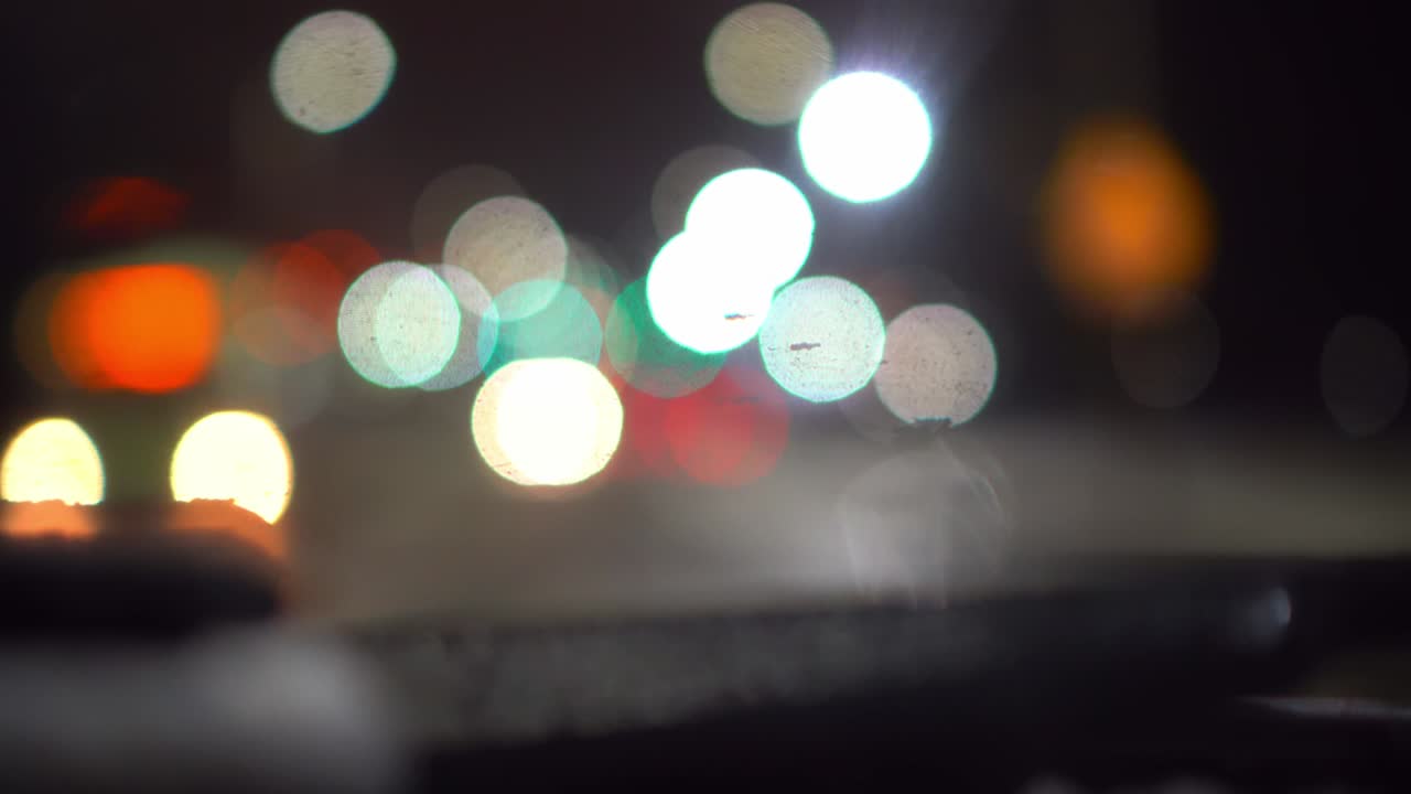 tráfico de automóviles en la ciudad nocturna, cámara dentro del automóvil. bokeh en fondo oscuro borroso