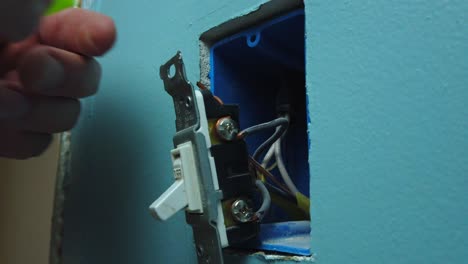 pulling a switch out of a wall box and unscrewing and removing two wires