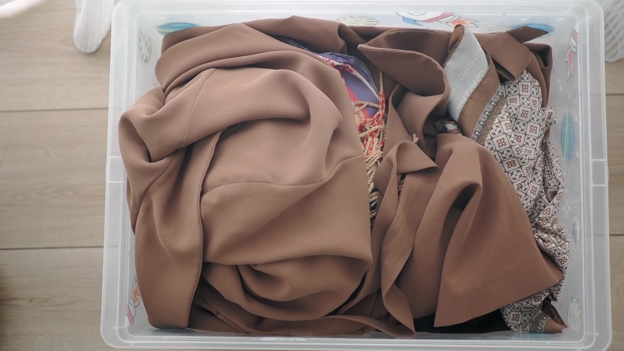 Clear Plastic Storage Bin Filled With Folded Clothing
