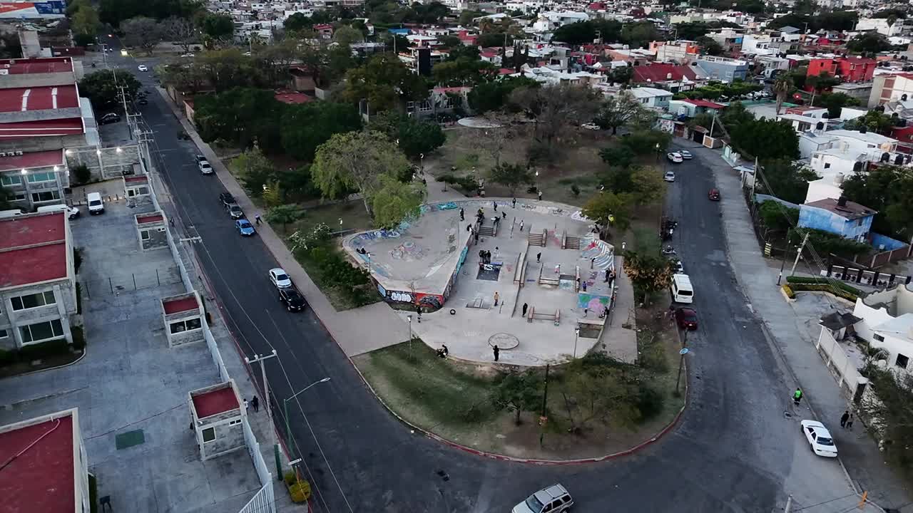 Um parque de skate urbano cercado por árvores e estradas, com atmosfera vibrante, vista aérea.