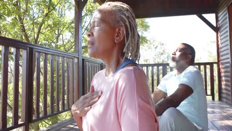 focused senior african american couple practicing yoga on sunny terrace, slow motion