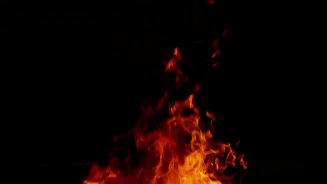 Splendida ripresa 4K senza soluzione di continuità di un falò dettagliato con vivaci fiamme arancioni e rosse su braci intense, isolato su uno sfondo nero puro. Perfetto per fusione, compositing e atmosfera