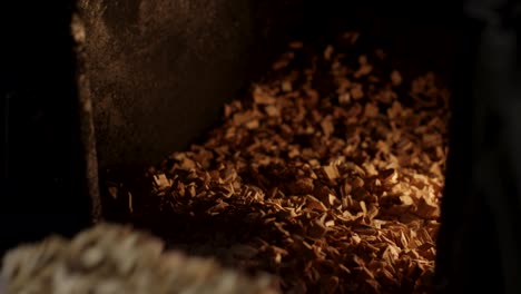 hands near a wood stove with burning wood chips