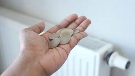 hand holding coins near a radiator