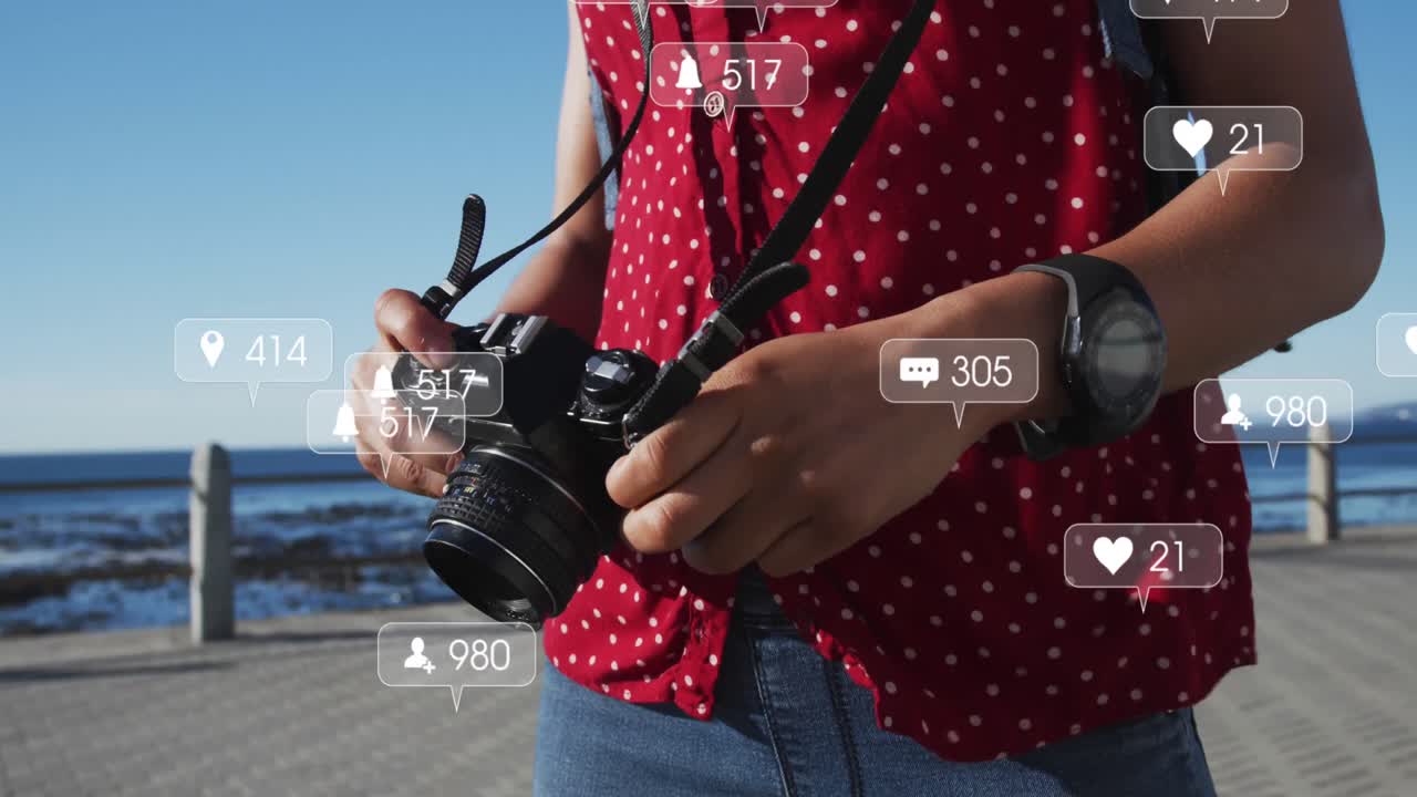 múltiples burbujas de habla con iconos digitales contra una mujer afroamericana con una cámara digital