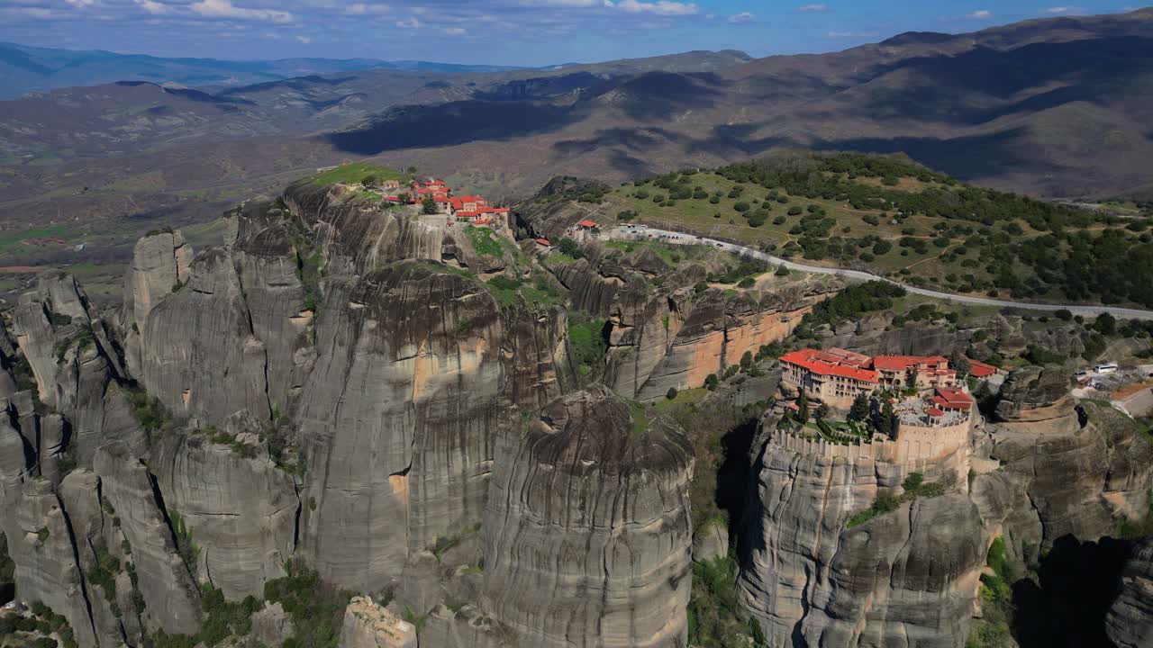 Drone wide of Meteora monasteries on dramatic cliffs near Kalambaka, Greece under blue sky