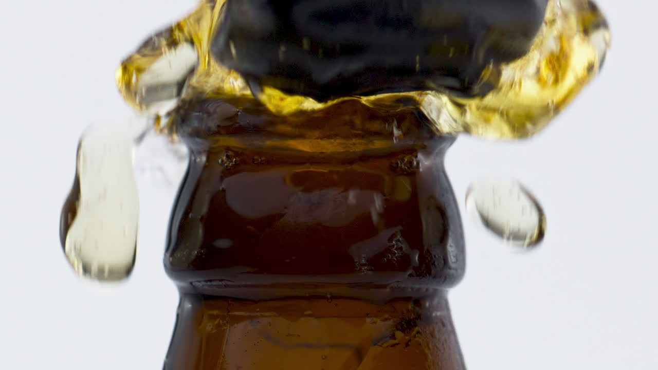 Bottiglia di birra fresca che zampilla in super slow motion in primo piano. Bevanda rinfrescante.