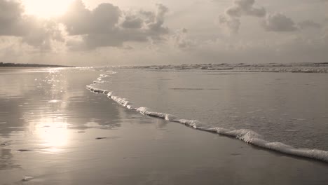 slow motion, close up, low angle of water lapping on beach at sunrise