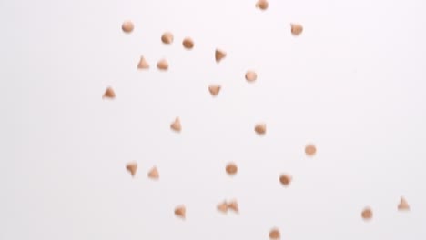 butterscotch caramel chips raining on white backdrop in slow motion