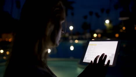 mujer con pad en el complejo tropical por la noche