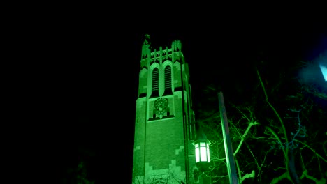 beaumont tower on the campus of michigan state university lit up at night in green in honor of the victims of the february, 2023 mass shooting with video walking by lamp