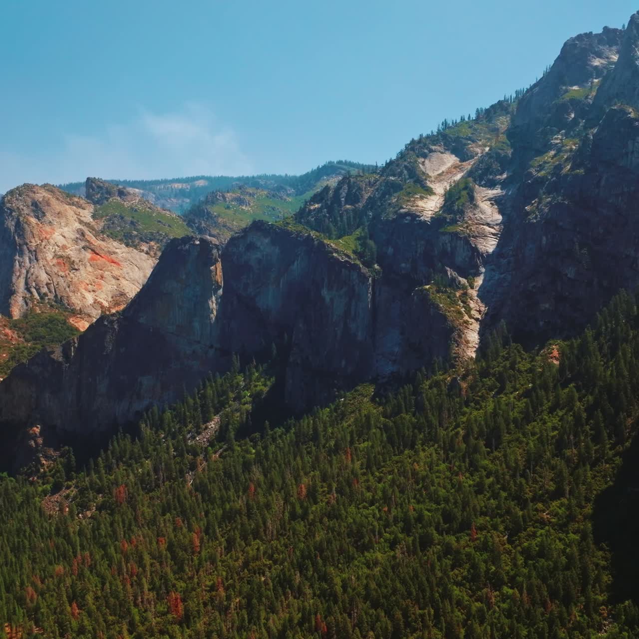 Beautiful rock formations in the United States National Park of Yosemite. Pine tree forest overgrowing the mountains. Sunny day clear sky backdrop