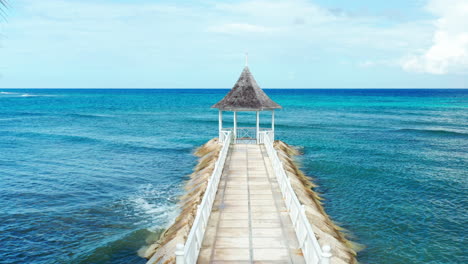 tropical beach view of broad walk leading to gazebo surrounded by turquoise caribbean ocean