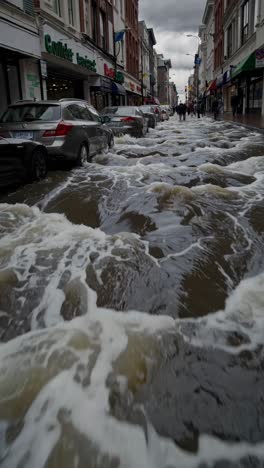 flooded street with cars partially submerged, water rushing, creating waves