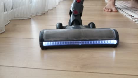 person cleaning wooden floor with vacuum cleaner