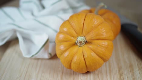 two small orange pumpkins on a cutting board