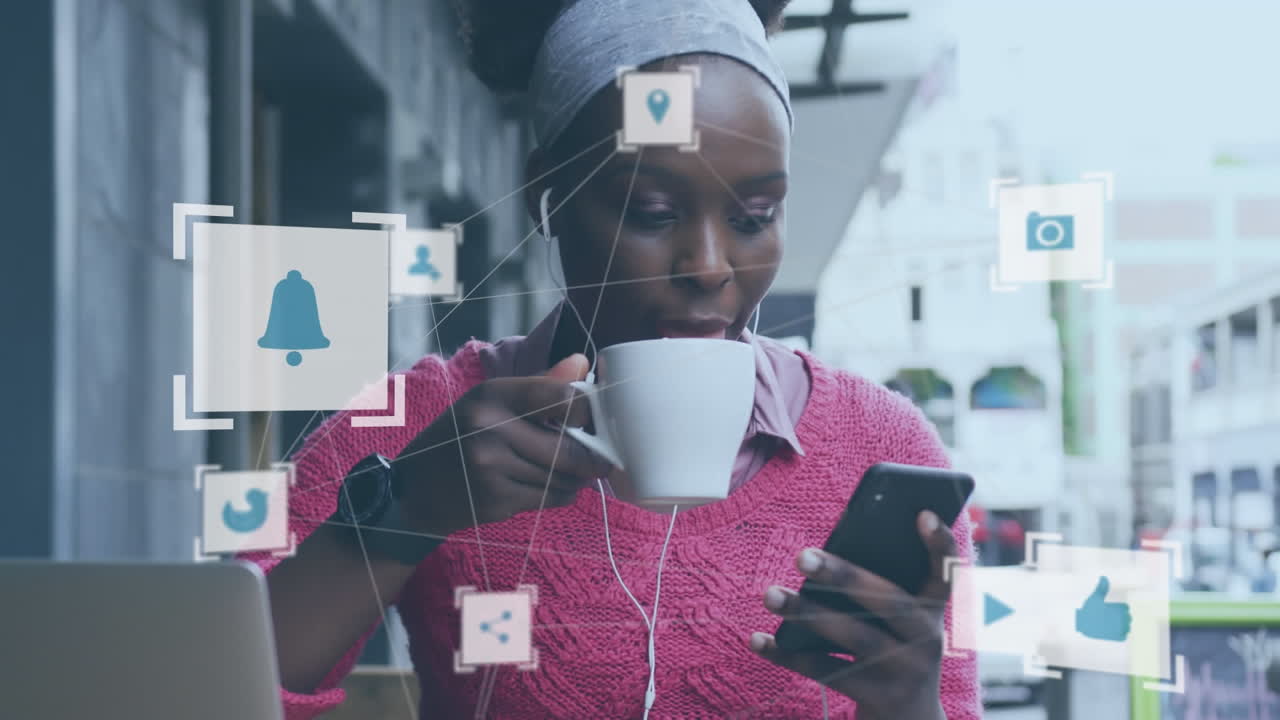 Animation of media icon network over happy african american woman using smartphone at street cafe