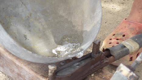 Molten-lead-being-poured-into-a-mold-at-a-construction-site,-daylight,-close-up