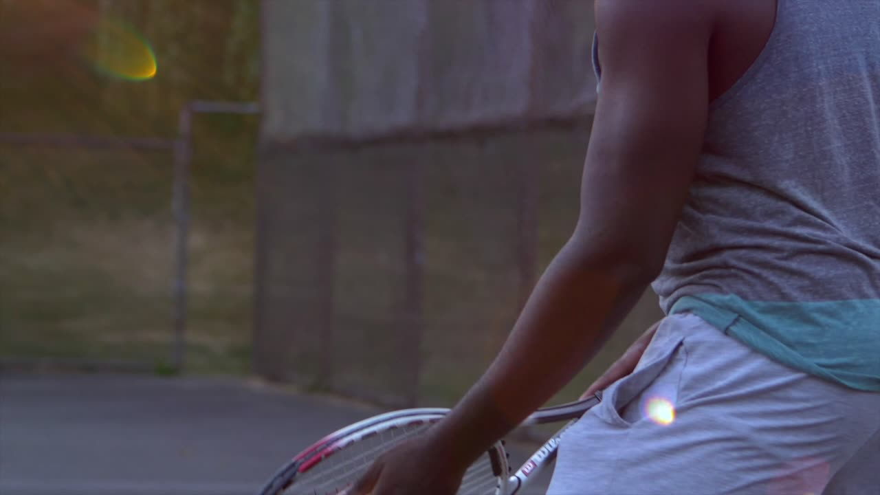 Close up of a Black Male Preparing himself before Serving a Tennis Ball to His Opponent during a Beautiful Sunset, Hastings Community Park