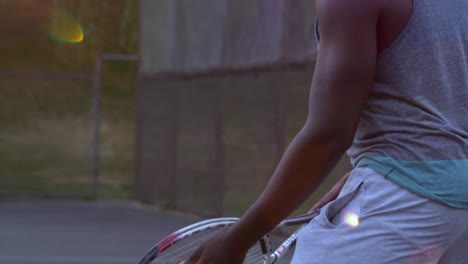 Close-up-of-a-Black-Male-Preparing-himself-before-Serving-a-Tennis-Ball-to-His-Opponent-during-a-Beautiful-Sunset,-Hastings-Community-Park