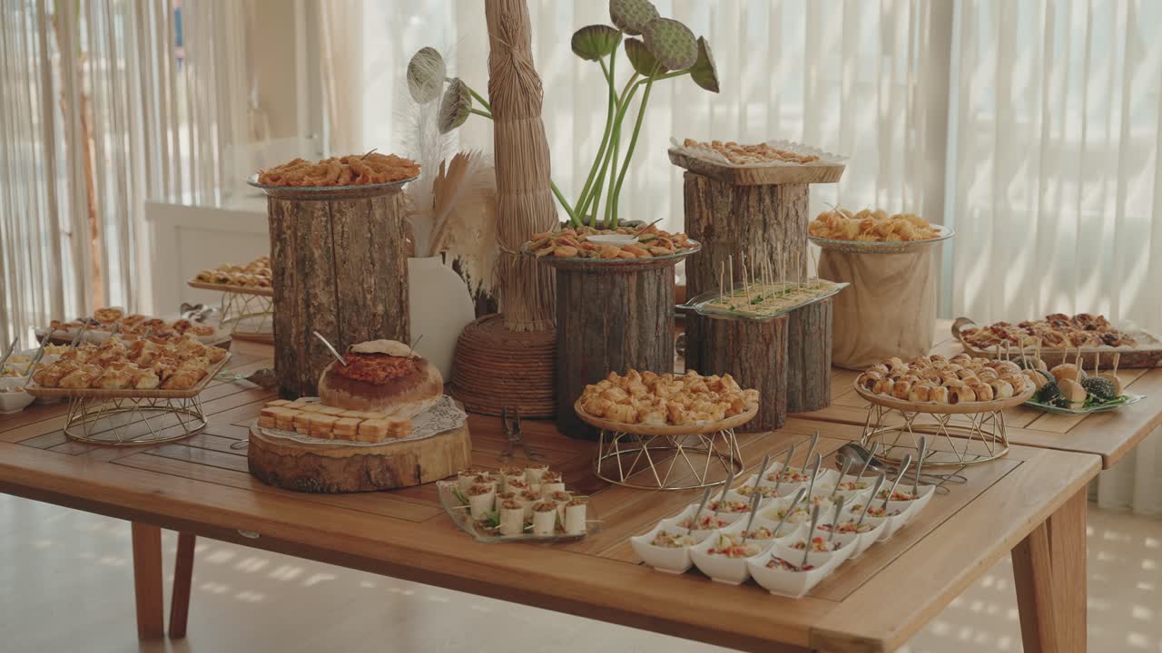 은은하고 따뜻한 빛 아래 여러 웨딩 에피타이저로 가득 채워진 소박한 뷔페 테이블