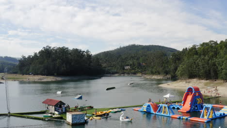 Gente-Disfrutando-De-Actividades-Acuáticas-En-El-Parque-Acuático-Teleski-En-La-Isla-De-Ermal,-Vieira-Do-Minho,-Portugal---Disparo-Ascendente-De-Drones