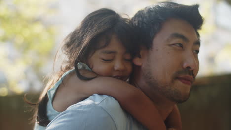 close-up of smiling young man giving his daughter a back ride at the park