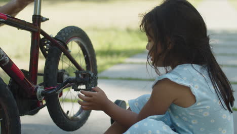 curious little girl looking at spinning pedals of her bike