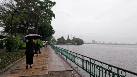 people walking by lake with umbrellas