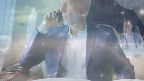 animación de conexiones y nubes sobre empresario caucásico senior usando teléfono inteligente en el avión