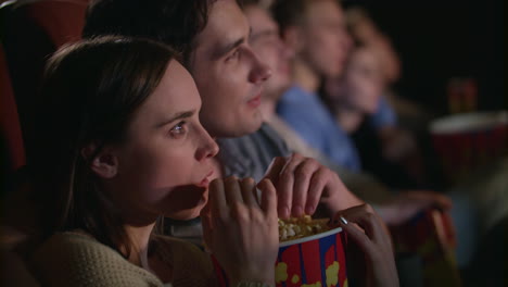 una pareja joven comiendo palomitas de maíz.