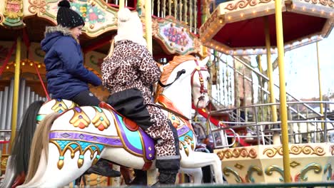young children ride colorful old-fashion carousel horses side by side, tivoli gardens, copenhagen, denmark, close up slow motion pan