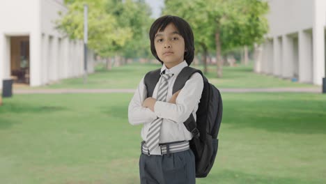 retrato de un niño de escuela indio confiado de pie con las manos cruzadas