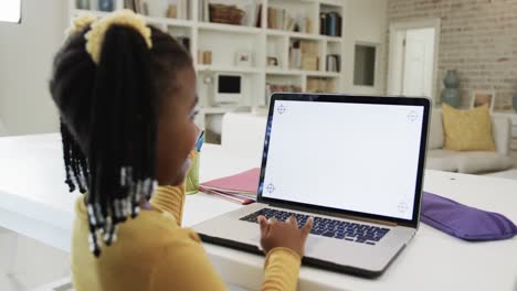 une fille afro-américaine heureuse en classe en ligne, utilisant un ordinateur portable avec un espace de copie à l'écran, au ralenti
