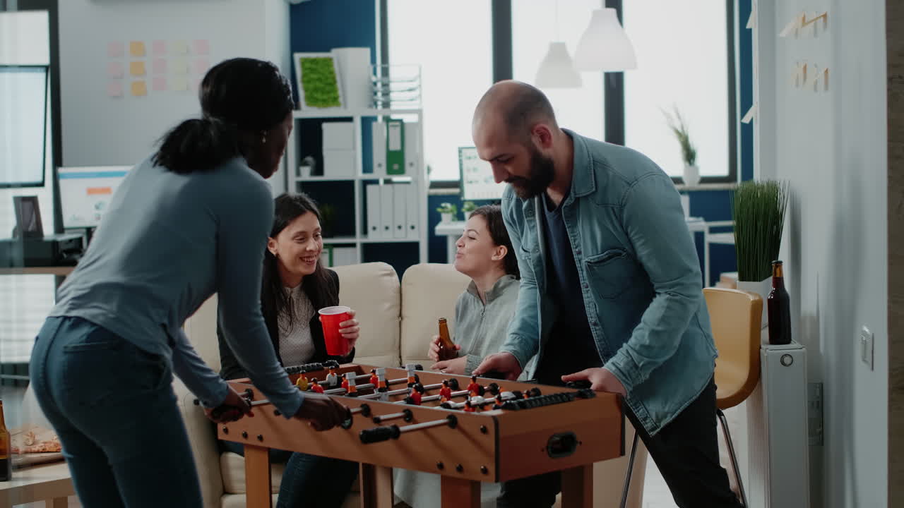 Diverse group of workmates enjoying game with foosball table