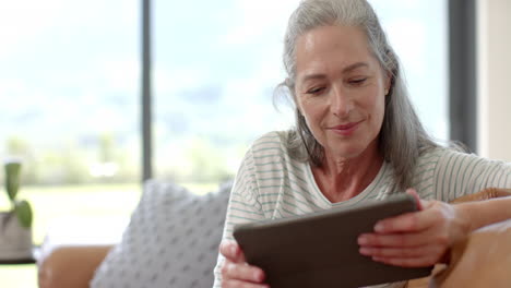 Eine-Reife-Kaukasische-Frau-Mit-Tablet-Auf-Einer-Couch-Sitzend