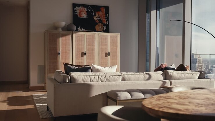 la vita di una casa in un condominio di alto livello con armadi di legno e un divano abbronzato accanto a grandi finestre che lasciano entrare la luce solare naturale