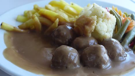 swedish meatballs with mashed potatoes, french fries, green beans and gravy