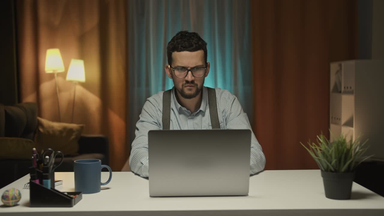 hombre árabe guapo trabaja en una computadora personal, señala la pantalla y muestra los pulgares hacia arriba. en el fondo acogedora sala de estar. en cámara lenta.